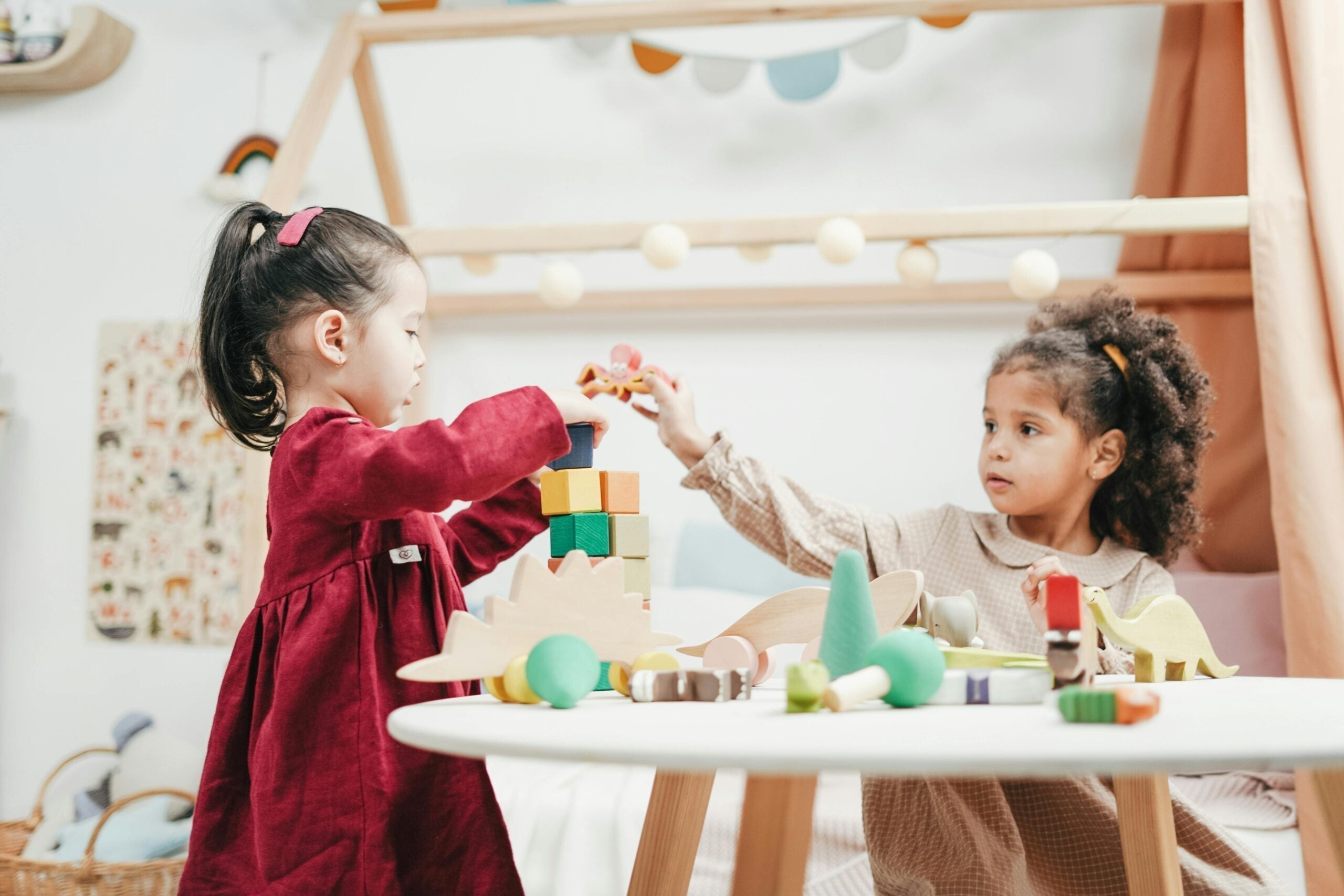 Two little girls playing with colourful blocks at a white round table