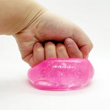 A hand squeezing a translucent pink squishy toy with embossed lettering Chilly Cube on a plain white background.