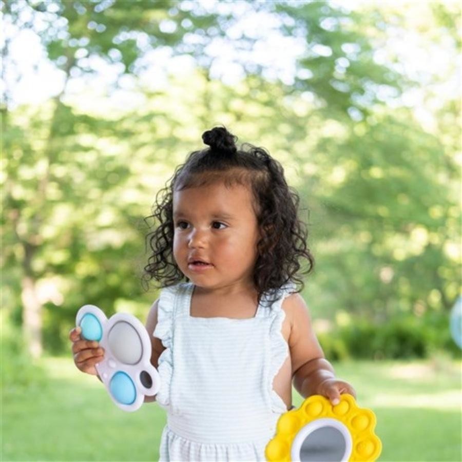 Child holding colorful toys outdoors with a blurred green background