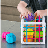 Child playing with colorful building blocks and a basket on a table.