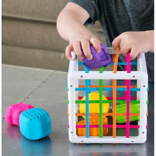 Child playing with colorful building blocks and a basket on a table.