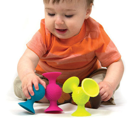 Child playing with colorful silicone suction cups on a white background