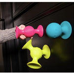 Colorful silicone door stoppers on a dark surface with a hand holding one.