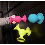 Colorful silicone door stoppers on a dark surface with a hand holding one.