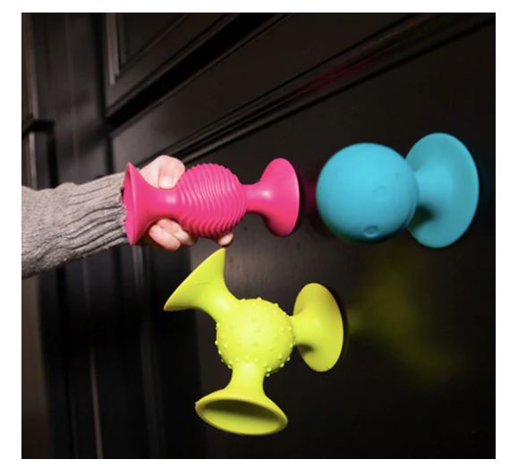 Colorful silicone door stoppers on a dark surface with a hand holding one.