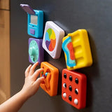 Colorful toy blocks on a dark surface with a child's hand interacting with one of them.