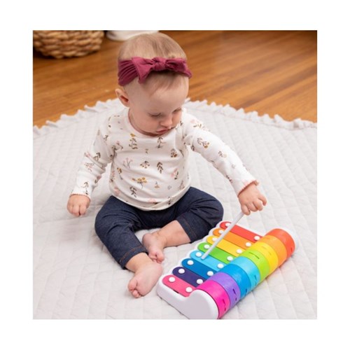 Baby playing with a colorful toy piano on a white blanket