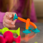 Child's hand playing with colorful siliconetoys on a reflective surface