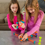 Two young girls playing with colorful building toys on a table.