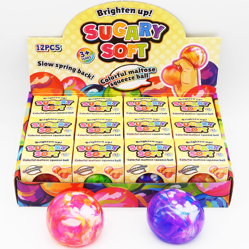 A display box of Sugary Soft Squeeze Balls. Three marbled  balls are placed in front of the box on a clean white background.