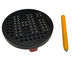 A black circular perforated plastic disc with many small metallic ball bearings shown next to a yellow-handled tool on a plain white background.