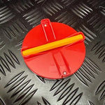 A red circular plastic pad with a yellow writing stylus across the center, photographed on a black diamond-plate metal surface.