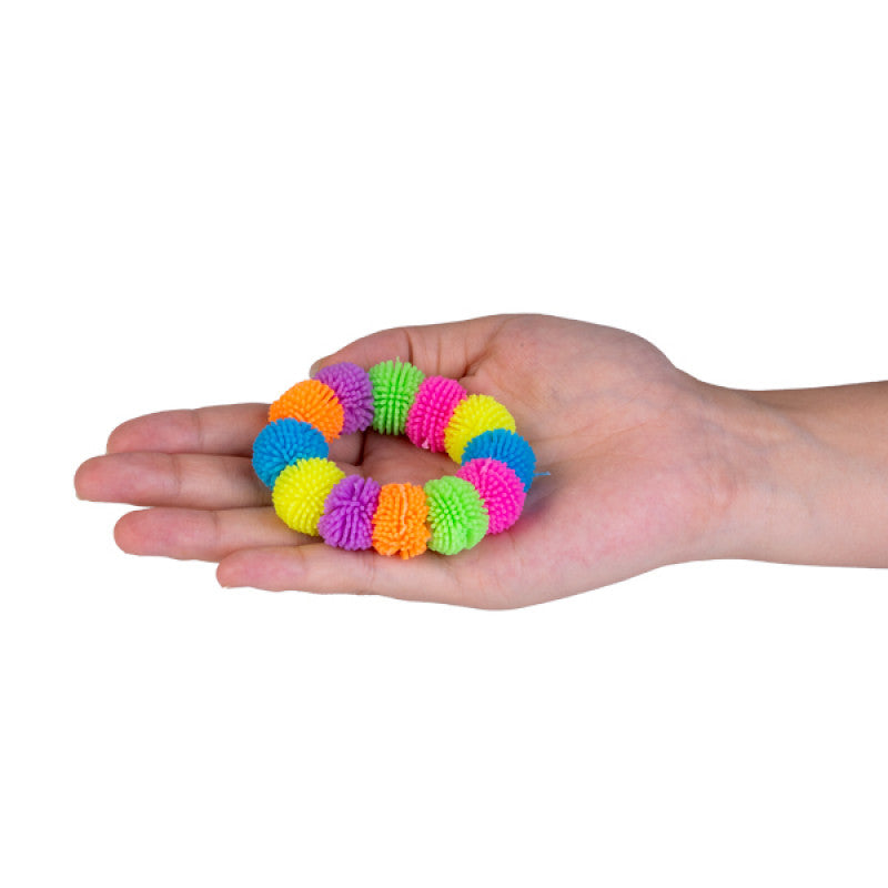 Colorful fuzzy ball bracelet held in a hand on a white background