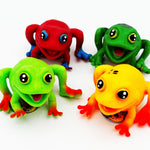 Four frog toys in red, green, yellow, and orange-red, arranged on a plain white background.